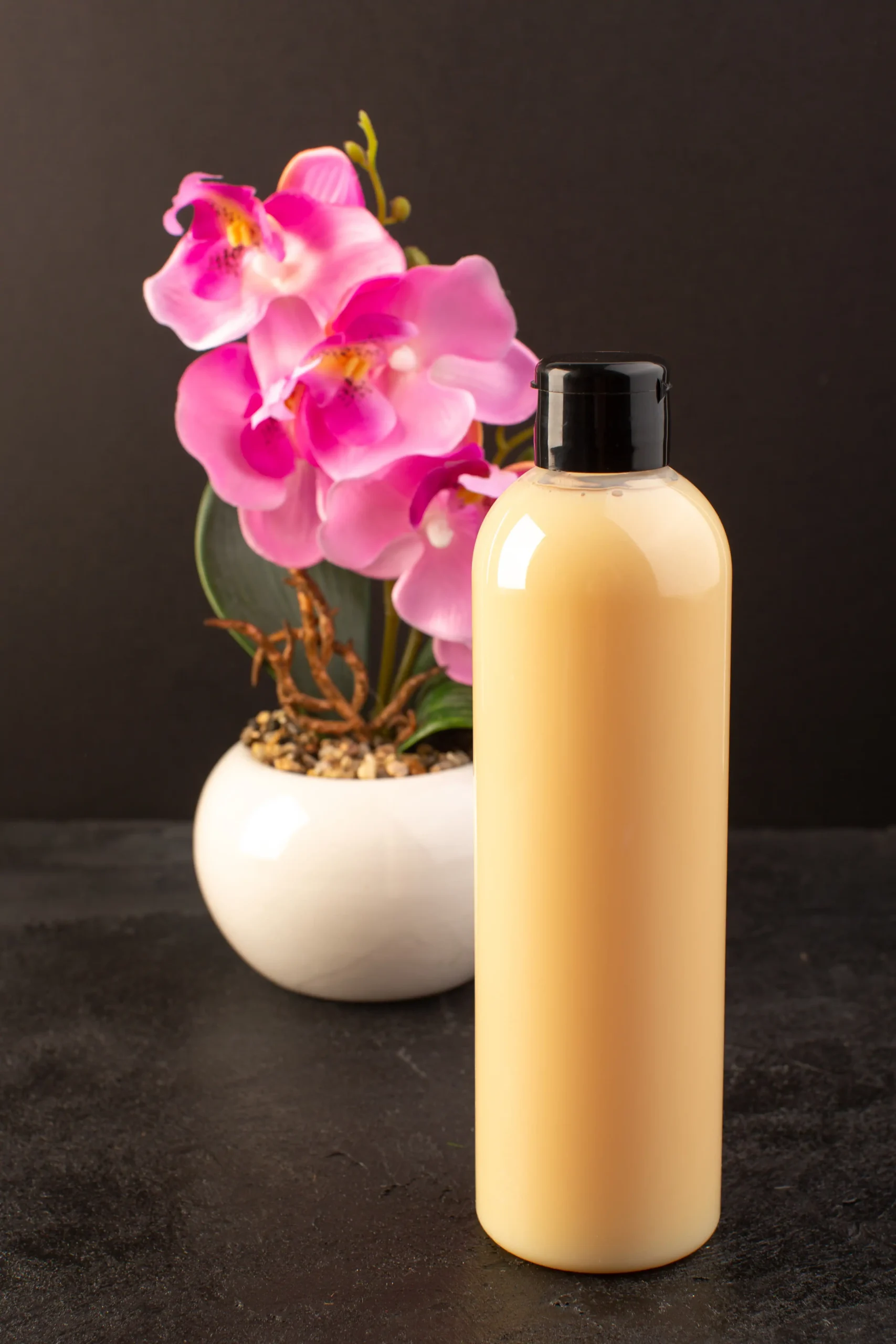 front-view-cream-colored-bottle-plastic-shampoo-can-with-black-cap-with-flower-isolated-dark-background-cosmetics-beauty-hair